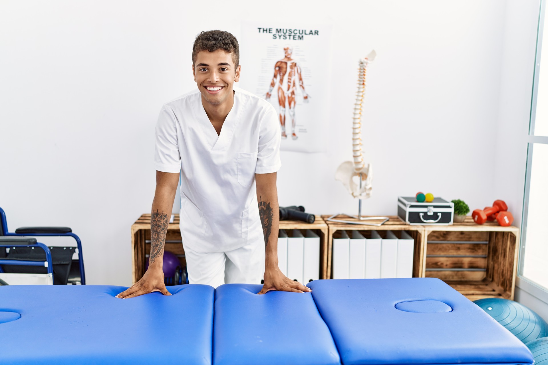 Young hispanic man working as physiotherapist at physiotherapy room